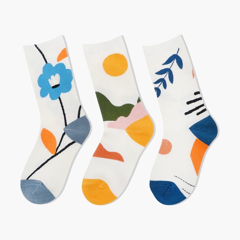 Three colorful socks with floral and abstract designs on a white background