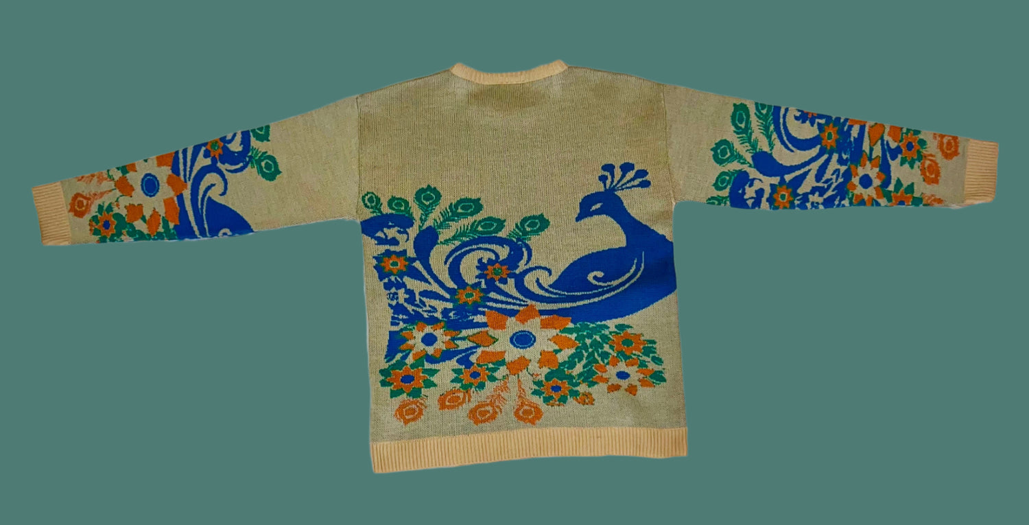 Sweater with peacock design on a white fabric background