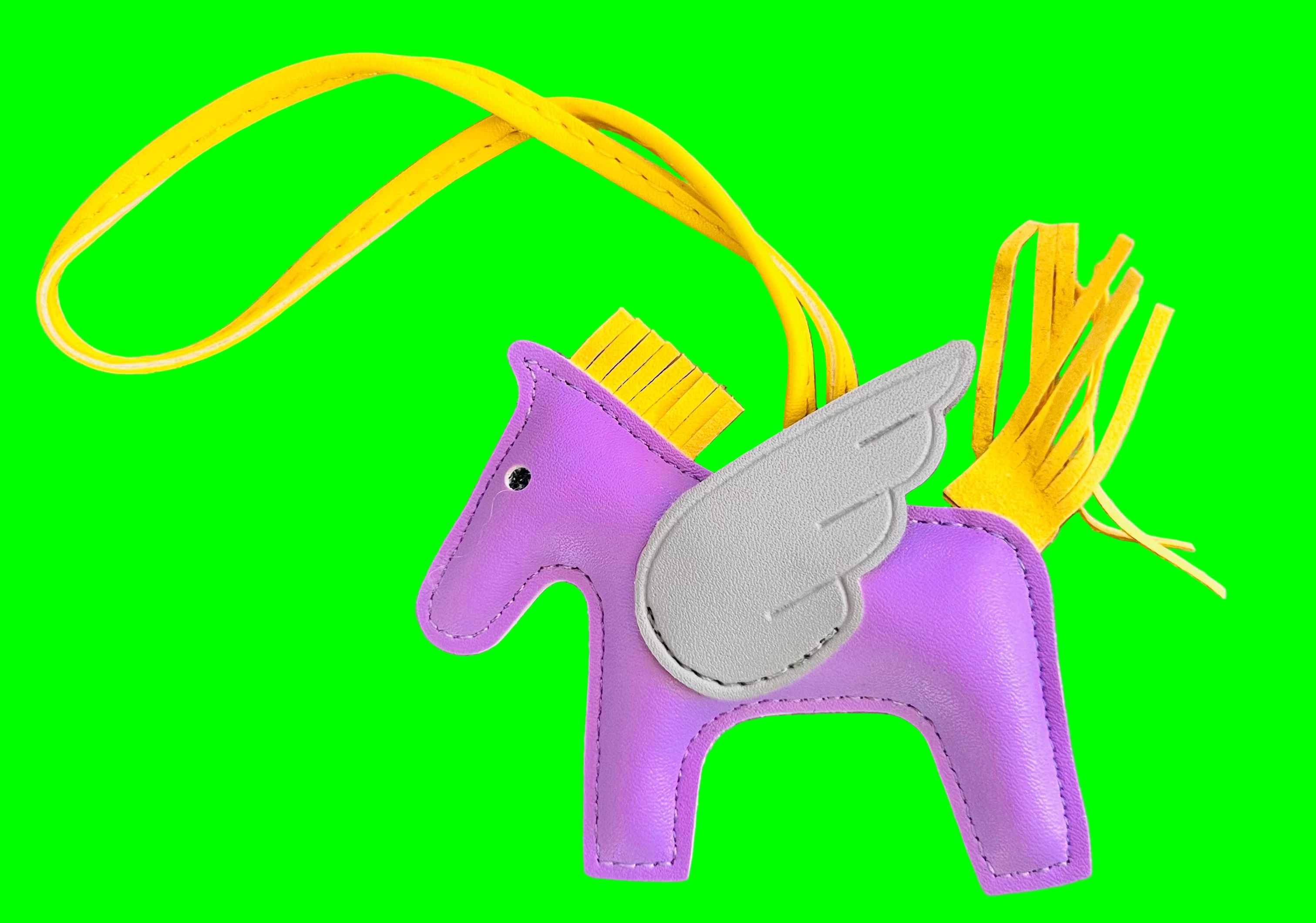 Purple horse-shaped keychain with yellow tassel on a gray background